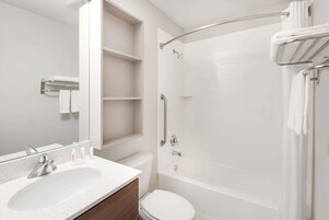 Un baño moderno con lavamanos, inodoro y bañera blancos.