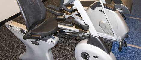 A row of stationary bikes in a gym with a blue carpet.