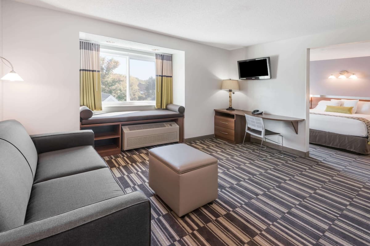 A hotel room with a sofa, a desk, a television, and a bed.
