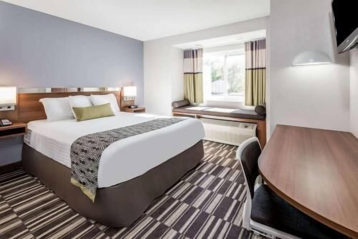 A hotel room with a bed, bedside tables, a desk, and a chair.