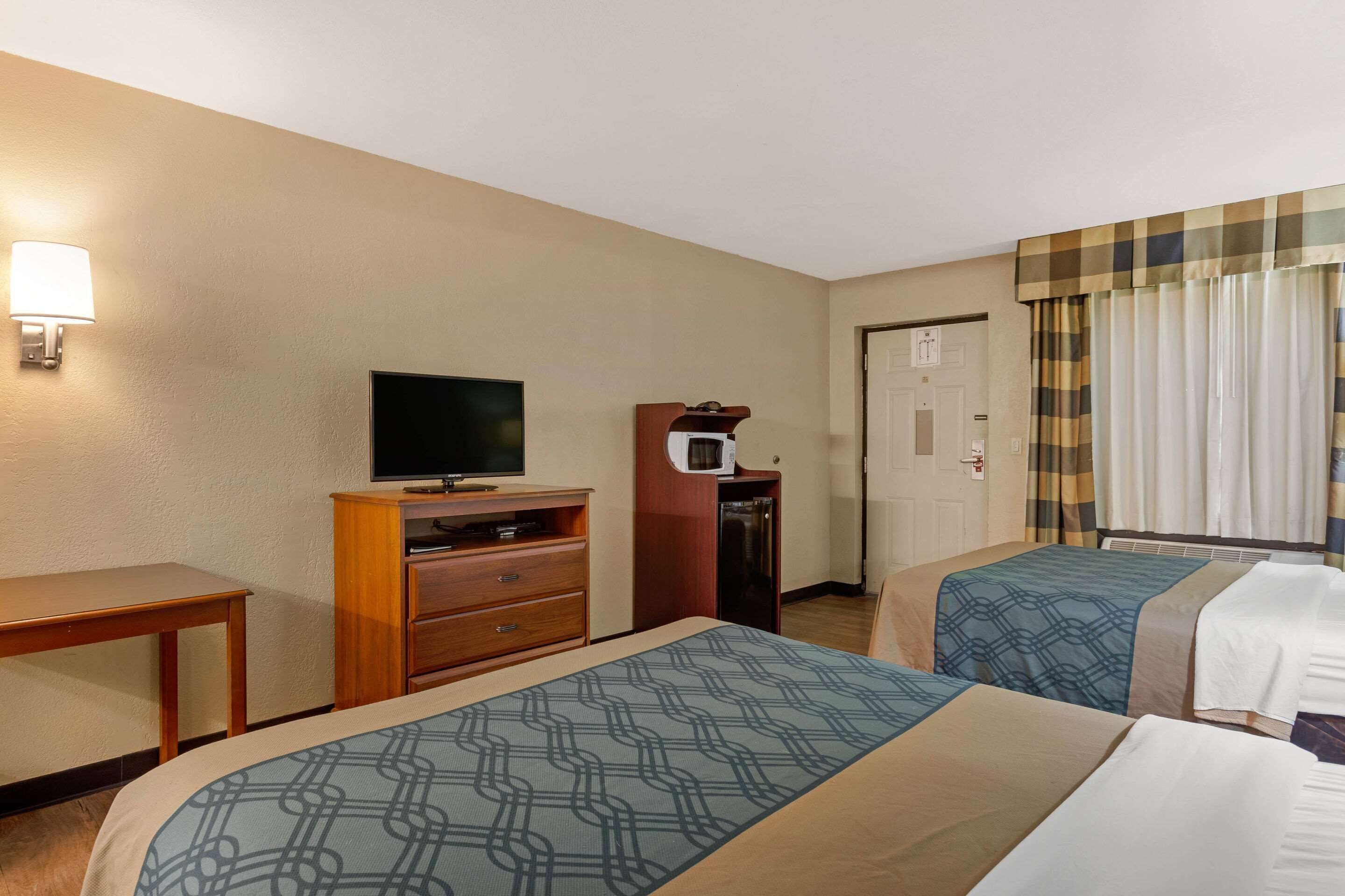 Een hotelkamer met twee bedden, een televisie, een bureau en een minibar.