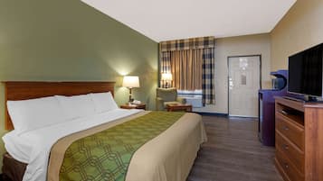 Una habitación de hotel con cama, escritorio, silla, televisor y puerta.
