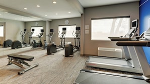 A gym with treadmills, elliptical machines, and a bench.