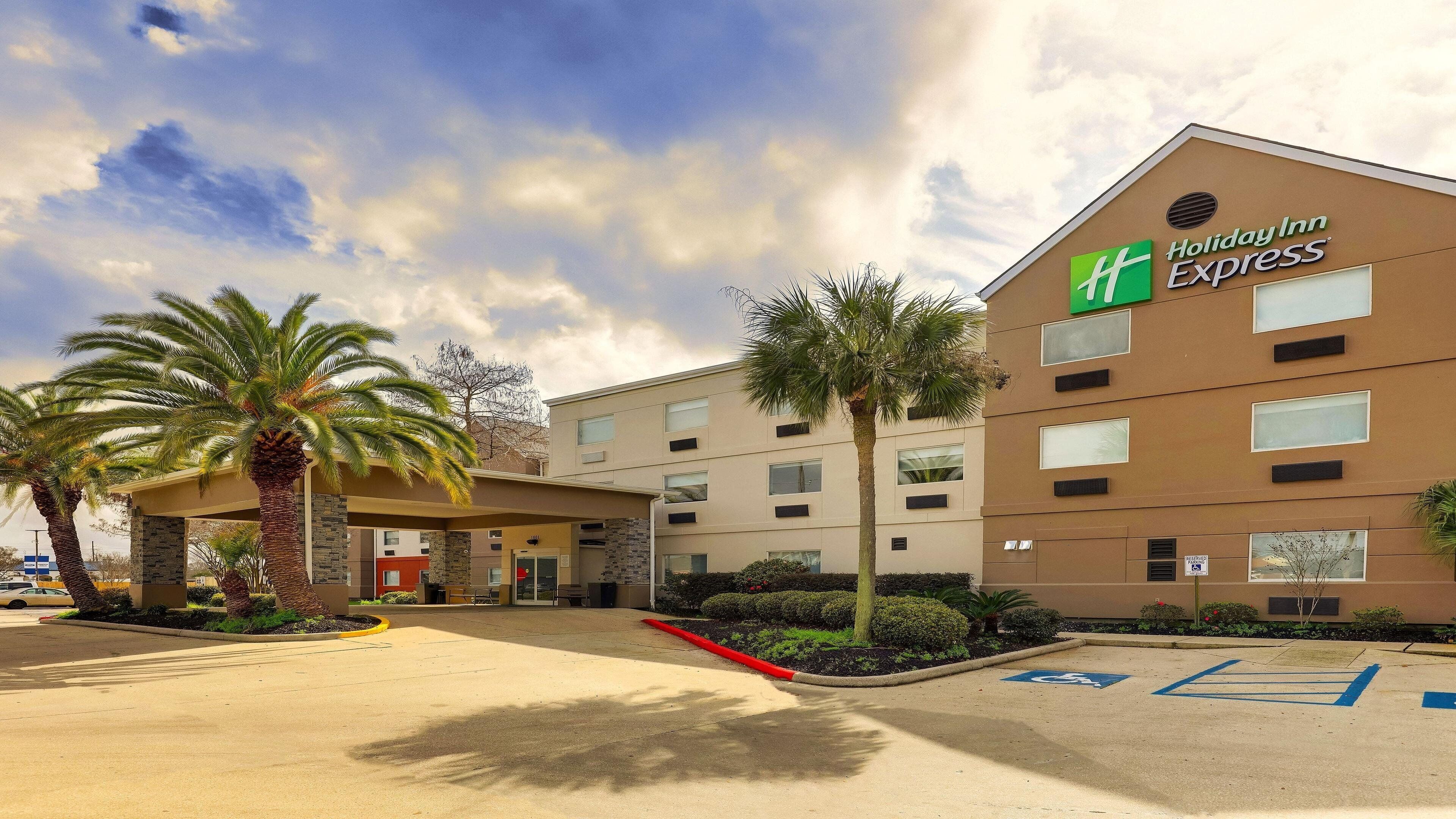 Een Holiday Inn Express gebouw met een modern ontwerp, voorzien van een plat dak en een ruime parkeerplaats met parkeerplaatsen voor mindervaliden.