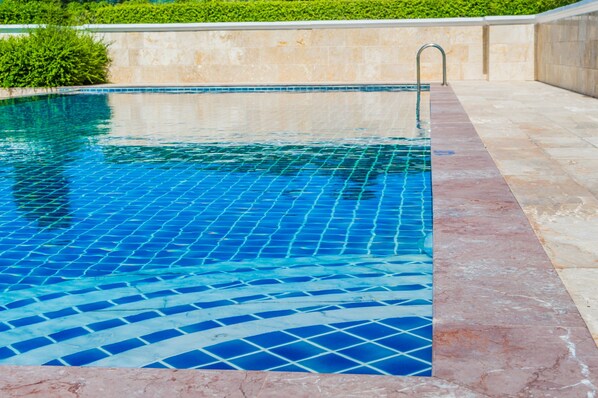 A swimming pool with a tiled edge and a metal ladder.