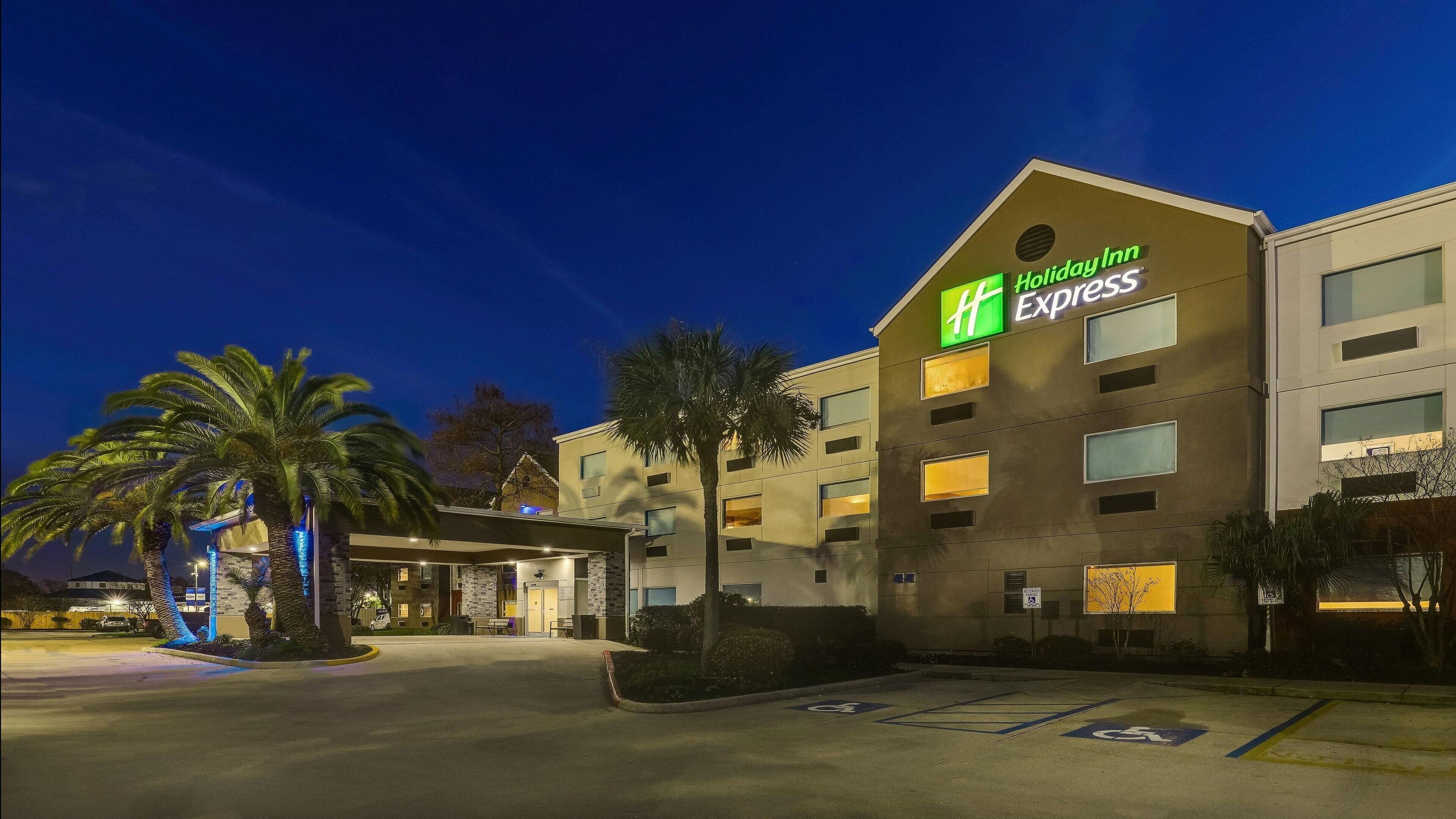 Edifici d'Holiday Inn Express de disseny modern, amb nombroses finestres i un aparcament amb senyalització d'accessibilitat per a persones amb discapacitat.