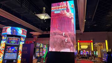 A casino with slot machines, a large digital screen advertising a game, and a Christmas tree.