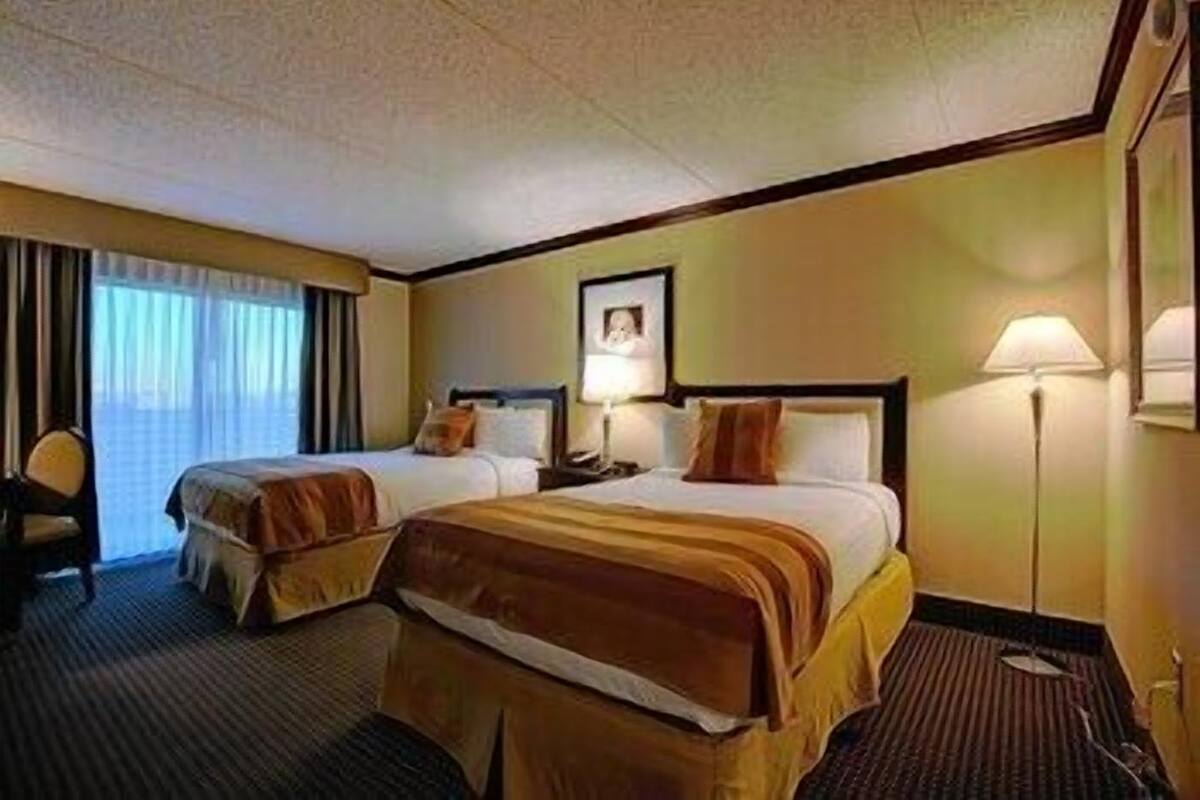Ein Hotelzimmer mit zwei Betten, einem Schreibtisch, einem Stuhl und einer Lampe.
