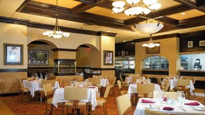 A restaurant with multiple tables set for dining, featuring a brick wall and wooden ceiling beams. - Hollywood Casino Tunica (Robinsonville)