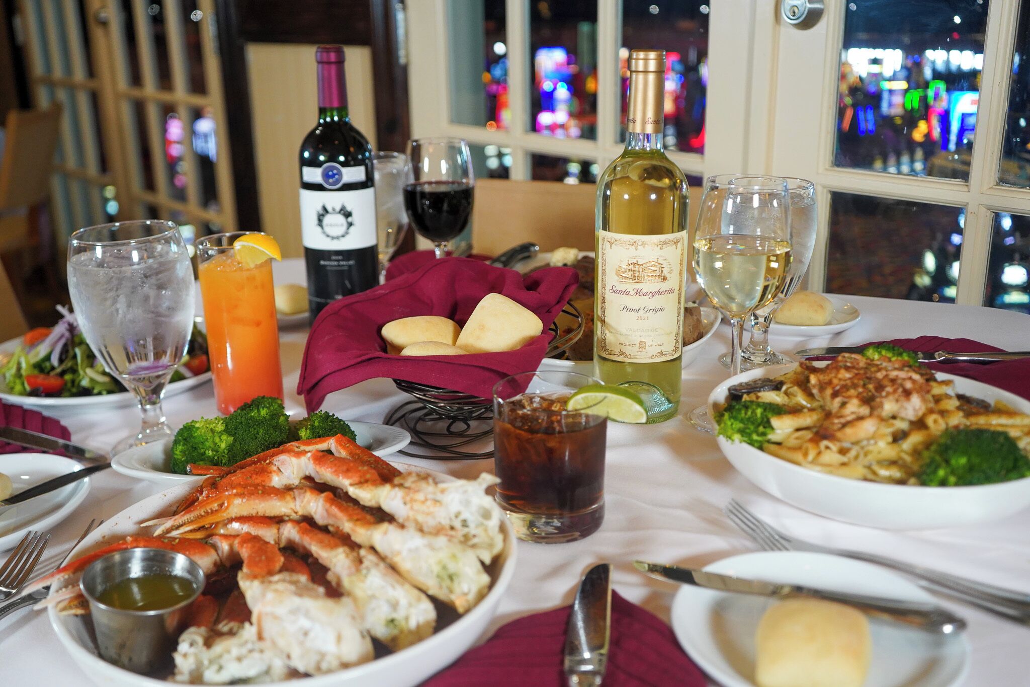 A dining table with seafood, wine glasses, and a bottle of wine.