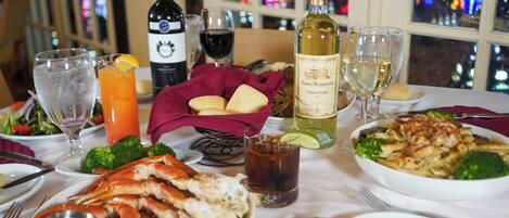 A dining table with seafood, wine glasses, and a bottle of wine.