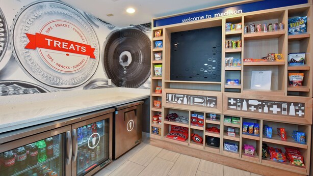 Un área de exhibición de snacks con un letrero que dice 'Treats', un letrero que dice 'Bienvenido a Madison' y varios artículos de snack en estantes.