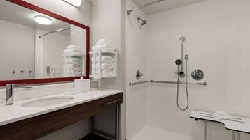 Un baño moderno con un espejo grande, un lavamanos, una ducha con cabezal de ducha manual y un perchero para toallas.