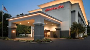 A Hampton Inn hotel entrance with a welcoming sign, a flag, and well-lit pillars. - Hampton Inn Starkville Mississippi State University (Starkville)
