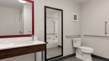 A bathroom with a white sink, a mirror, a toilet, and a shower area.