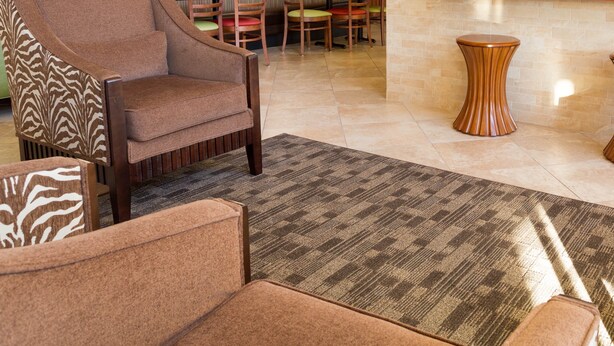 A hotel lobby with a seating area, a flat-screen TV mounted on the wall, and a patterned rug on the floor. - Drury Inn & Suites Atlanta Marietta (Marietta)