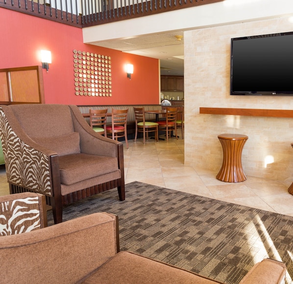 A hotel lobby with a seating area, a flat-screen TV mounted on the wall, and a patterned rug on the floor. - Drury Inn & Suites Atlanta Marietta (Marietta)