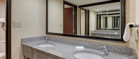 A bathroom with two sinks, a large mirror, and a towel rack.