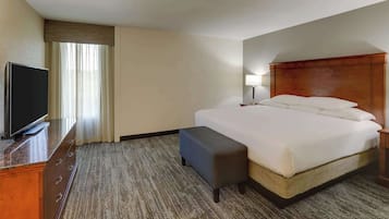 Una habitación de hotel con una cama, televisor, escritorio y lámpara.