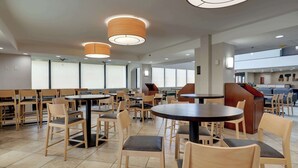 A spacious indoor dining area with multiple round tables and chairs, ceiling fans, and large windows allowing natural light. - Drury Inn & Suites Atlanta Marietta (Marietta)