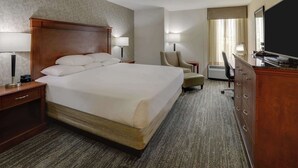 A hotel room with a large bed, bedside lamps, a desk with a chair, a television, and a wardrobe. - Drury Inn & Suites Atlanta Marietta (Marietta)