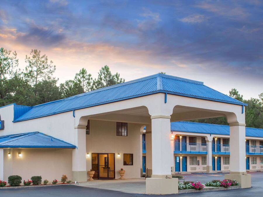 Un Days Inn con techo azul, entrada cubierta y una fila de habitaciones.