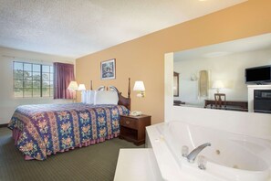 A hotel room with a large bed, a sitting area with a chair, a desk, a television, and a bathtub. - Days Inn by Wyndham Picayune (Picayune)