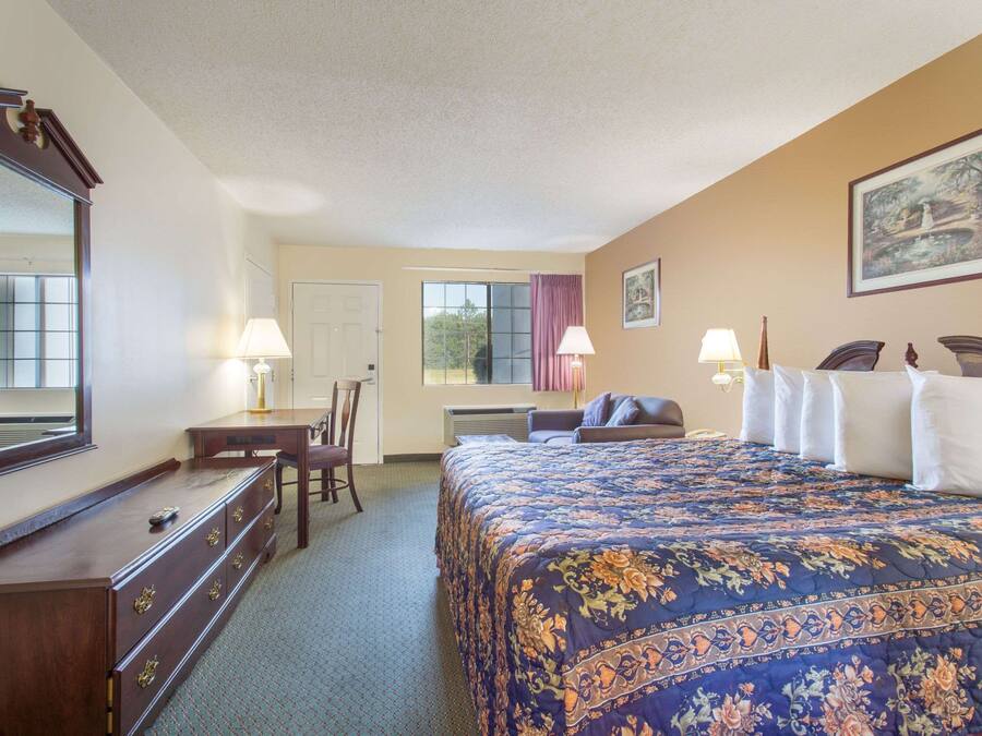 Una habitación de hotel con una cama grande, un aparador, un escritorio y una silla.