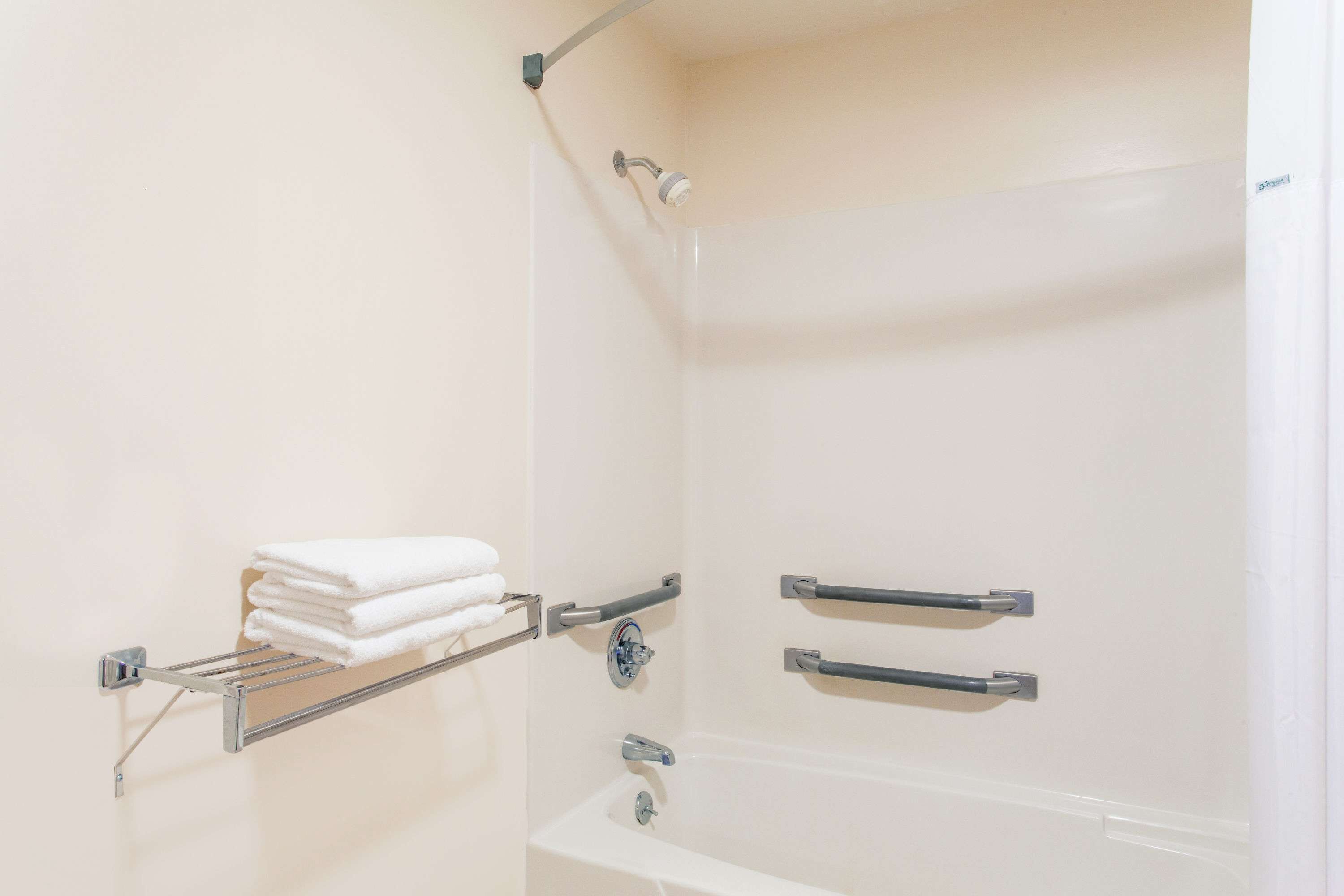 Un baño moderno con bañera, barras de apoyo y un perchero para toallas.