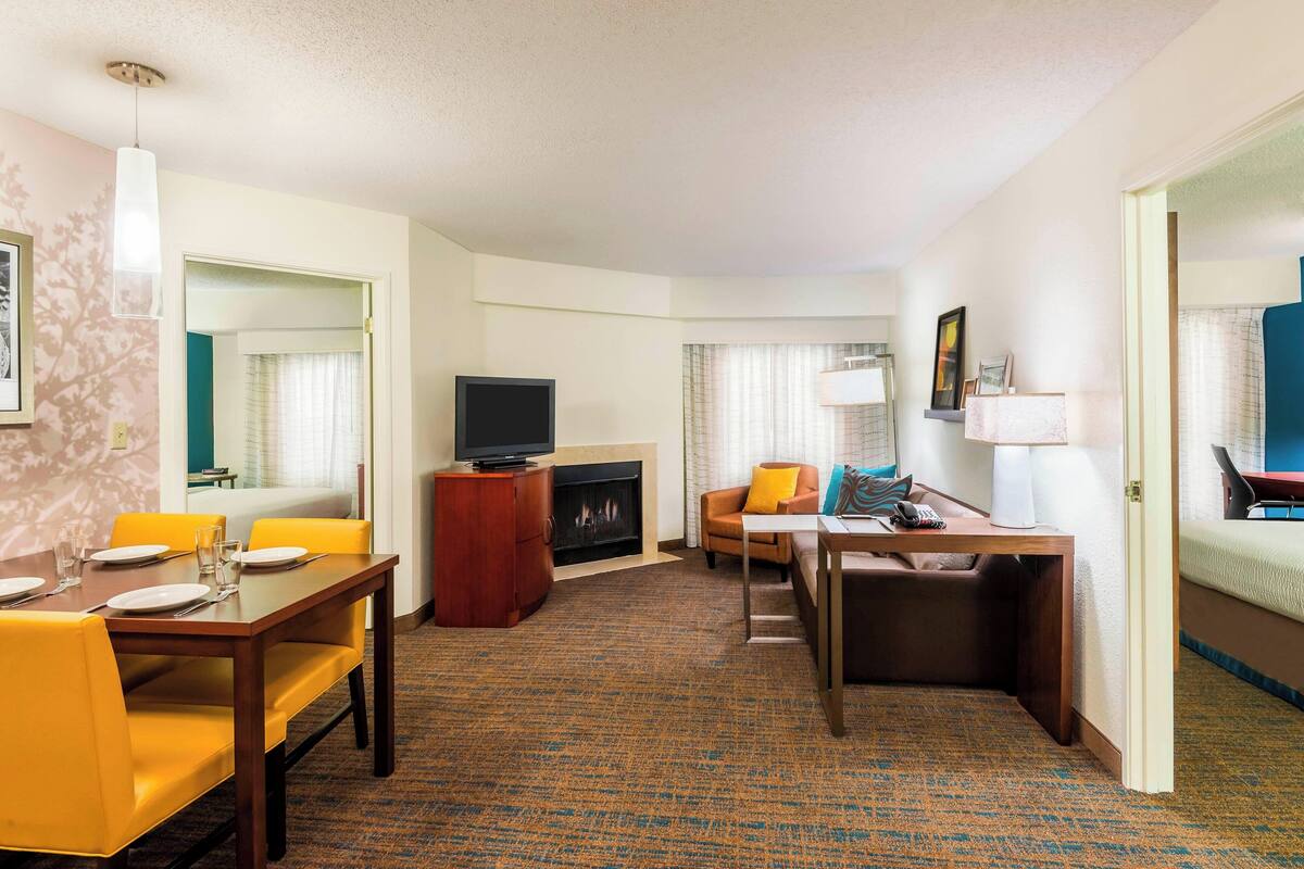Ein Hotelzimmer mit Essbereich, Fernseher, Kamin und Bett.