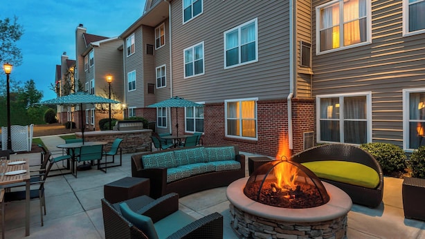A patio area with outdoor seating, a fire pit, and a brick wall.