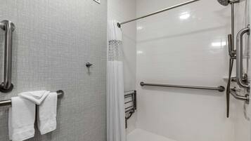 A bathroom with a shower, grab bars, and a towel rack.