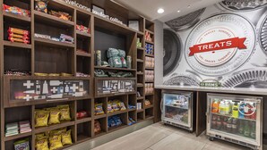 Un espace dédié à la présentation des collations et des boissons, avec des étagères remplies de diverses collations et un compartiment réfrigéré pour les boissons.