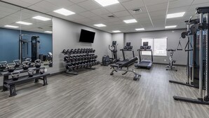 Une salle de sport équipée de supports à poids, de tapis de course et d’autres appareils d’exercice.