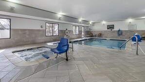 Une piscine intérieure avec un jacuzzi, une chaise bleue et un panneau indiquant qu’il est interdit de plonger.