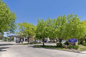 A Hampton Inn sign in a parking lot with trees and buildings in the background.