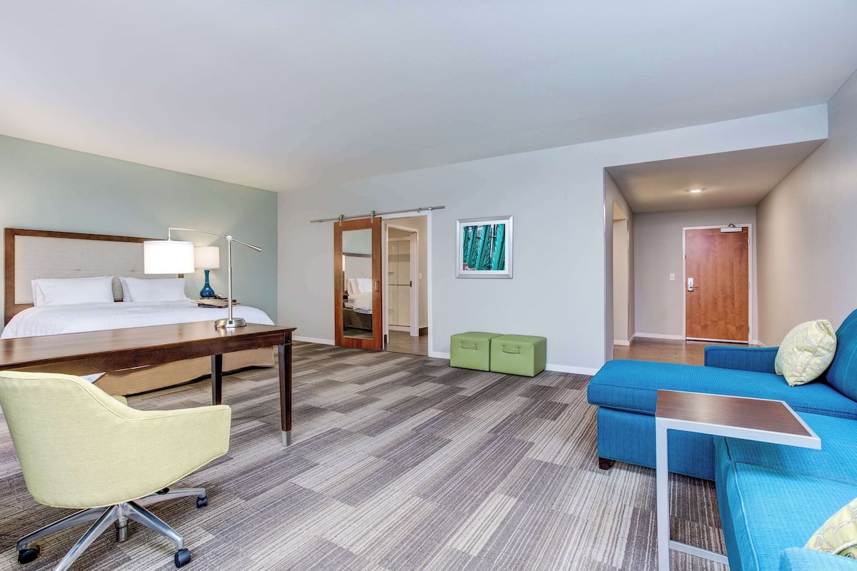 Ein Hotelzimmer mit Bett, Schreibtisch, Stuhl, Sofa und einem kleinen Tisch.
