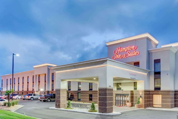 Um Hampton Inn & Suites com fachada moderna, entrada coberta e estacionamento.