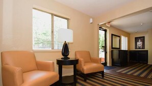 A hotel room with two leather armchairs, a small table with a lamp, and a striped carpet.