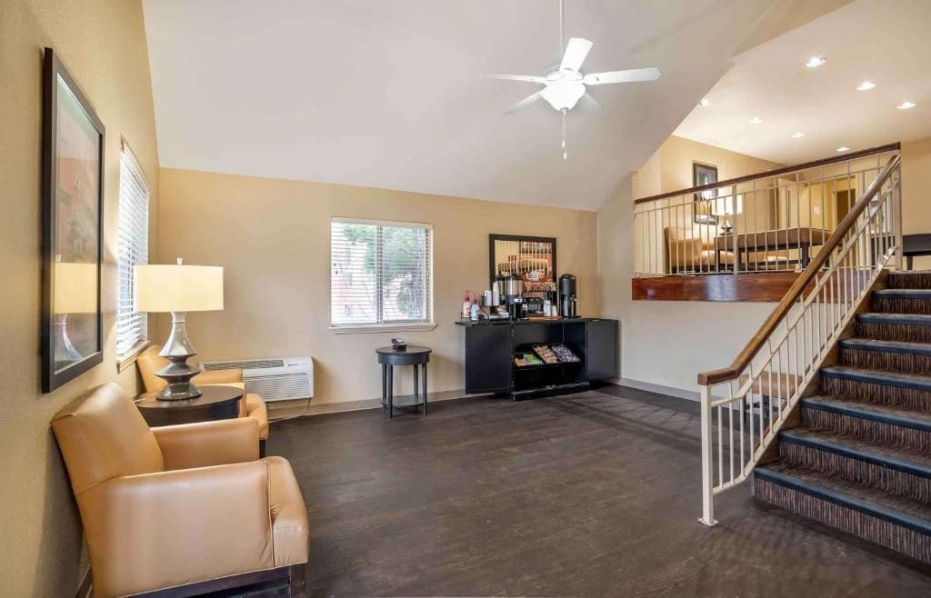 A spacious living area with a high ceiling, a fireplace, a staircase, and a ceiling fan.