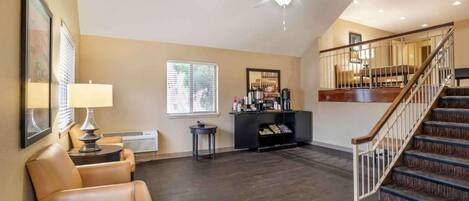 A spacious living area with a high ceiling, a fireplace, a staircase, and a ceiling fan.