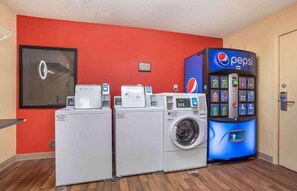 A laundry area with three washing machines and a Pepsi vending machine. - Studio 6 Suites Jackson Ridgeland MS (Ridgeland)