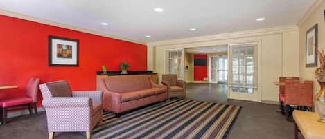 A spacious lobby with a red accent wall, a striped rug, and a sofa.