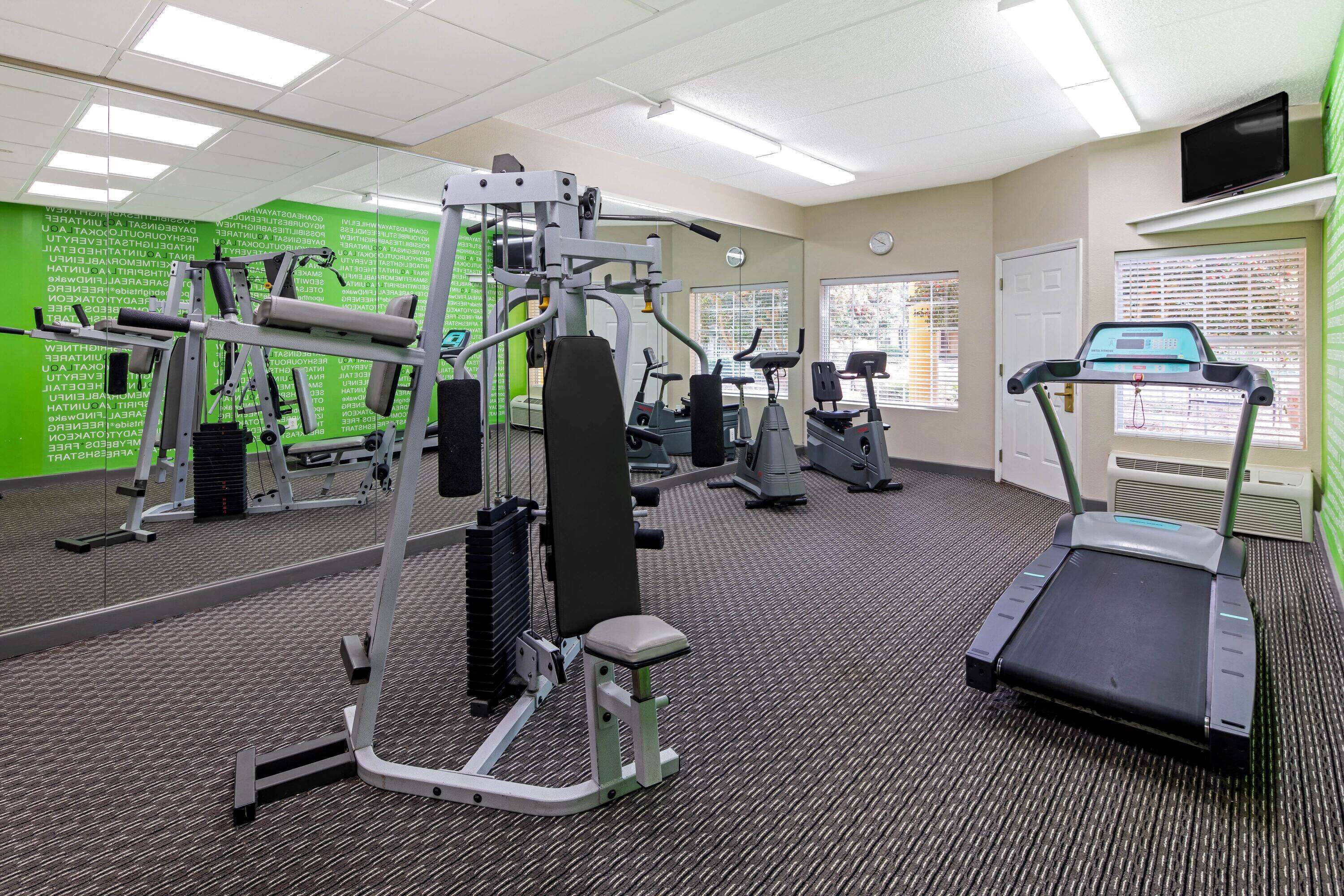 A gym with various exercise equipment, a treadmill, and a mirrored wall.