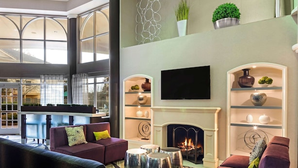 A modern living room with a fireplace, comfortable seating, and decorative shelves. - La Quinta Inn & Suites by Wyndham Macon (Macon)
