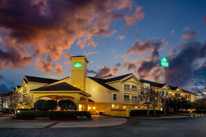 A hotel with a prominent sign, a large parking lot, and a well-lit entrance. - La Quinta Inn & Suites by Wyndham Macon (Macon)