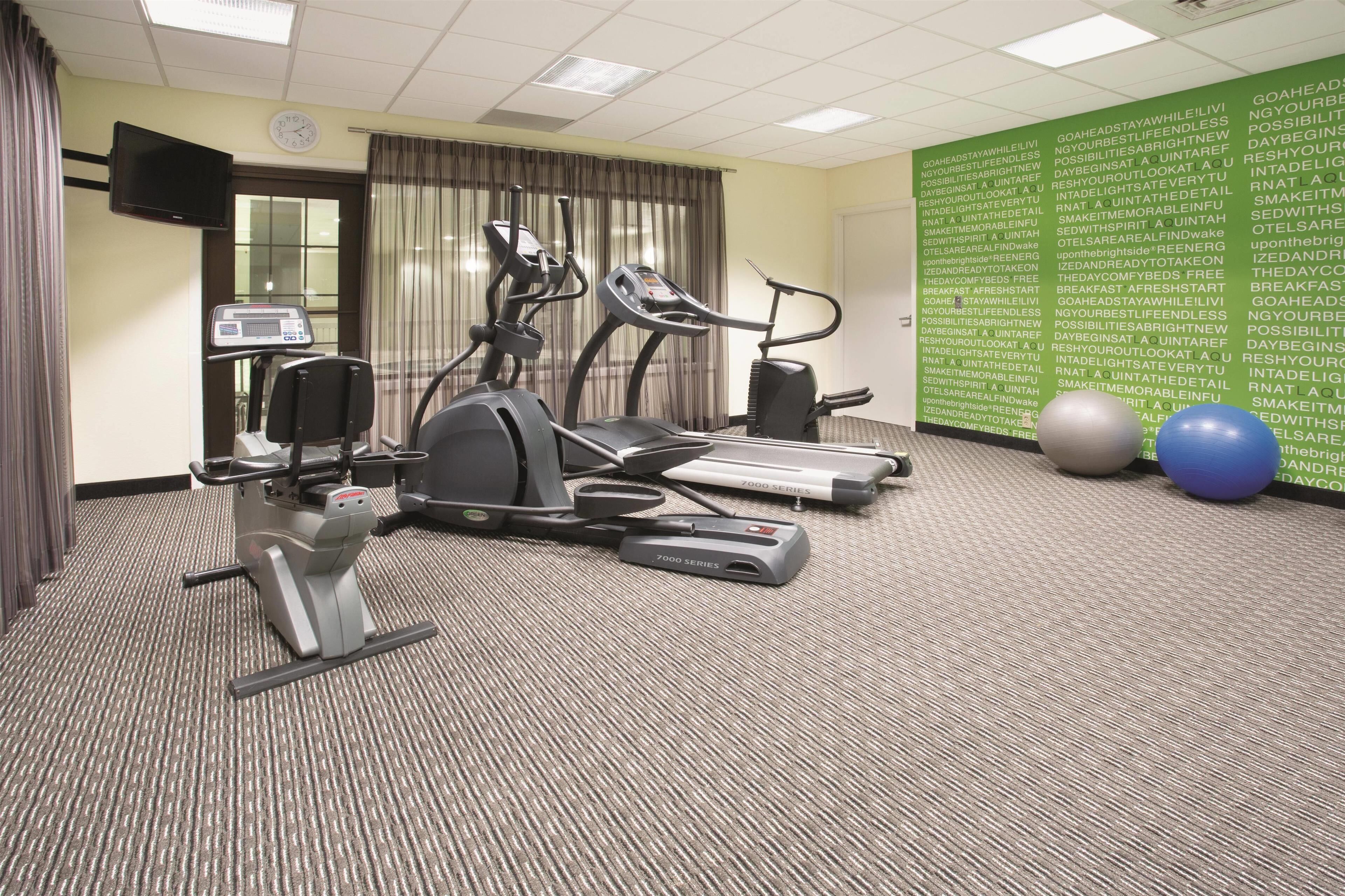 A fitness room with treadmills, a stationary bike, and exercise balls.