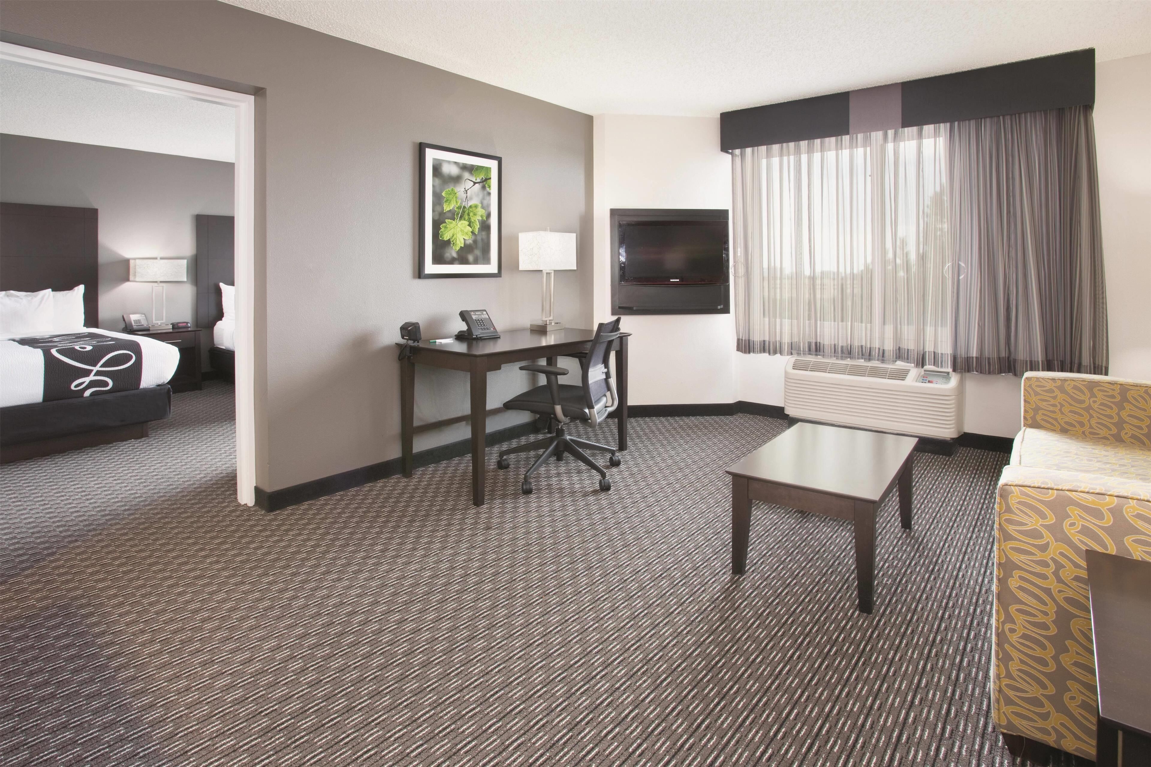 A hotel room with a bed, desk, chair, and a television.