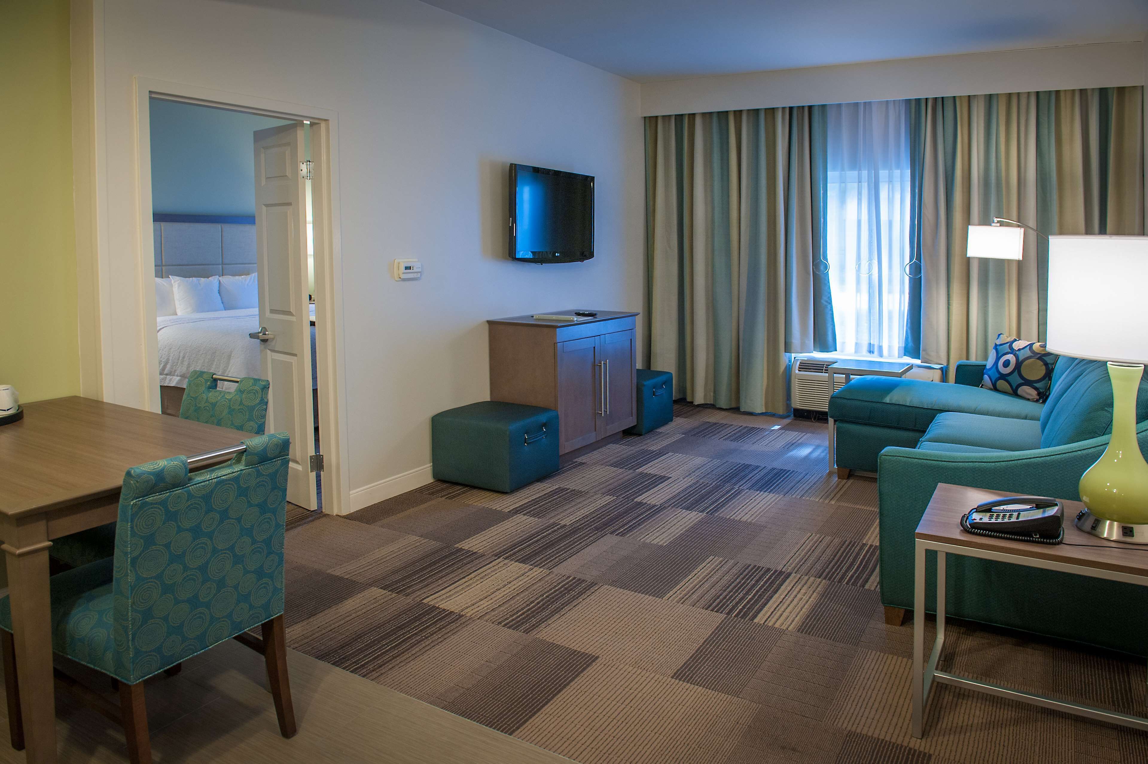 Habitación de hotel con cama, televisor, escritorio, sofá y zona de comedor.