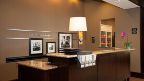 A reception desk with framed pictures, a lamp, and a sign reading "Manager On Duty".